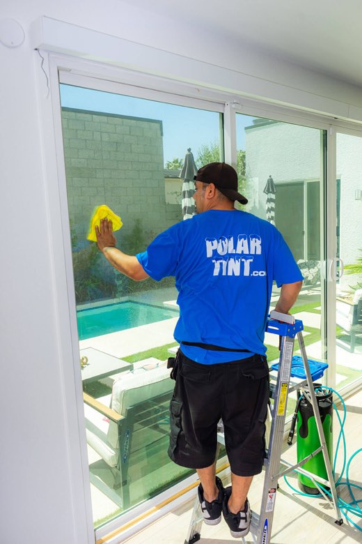 Polar Tint installer applying window film at a home